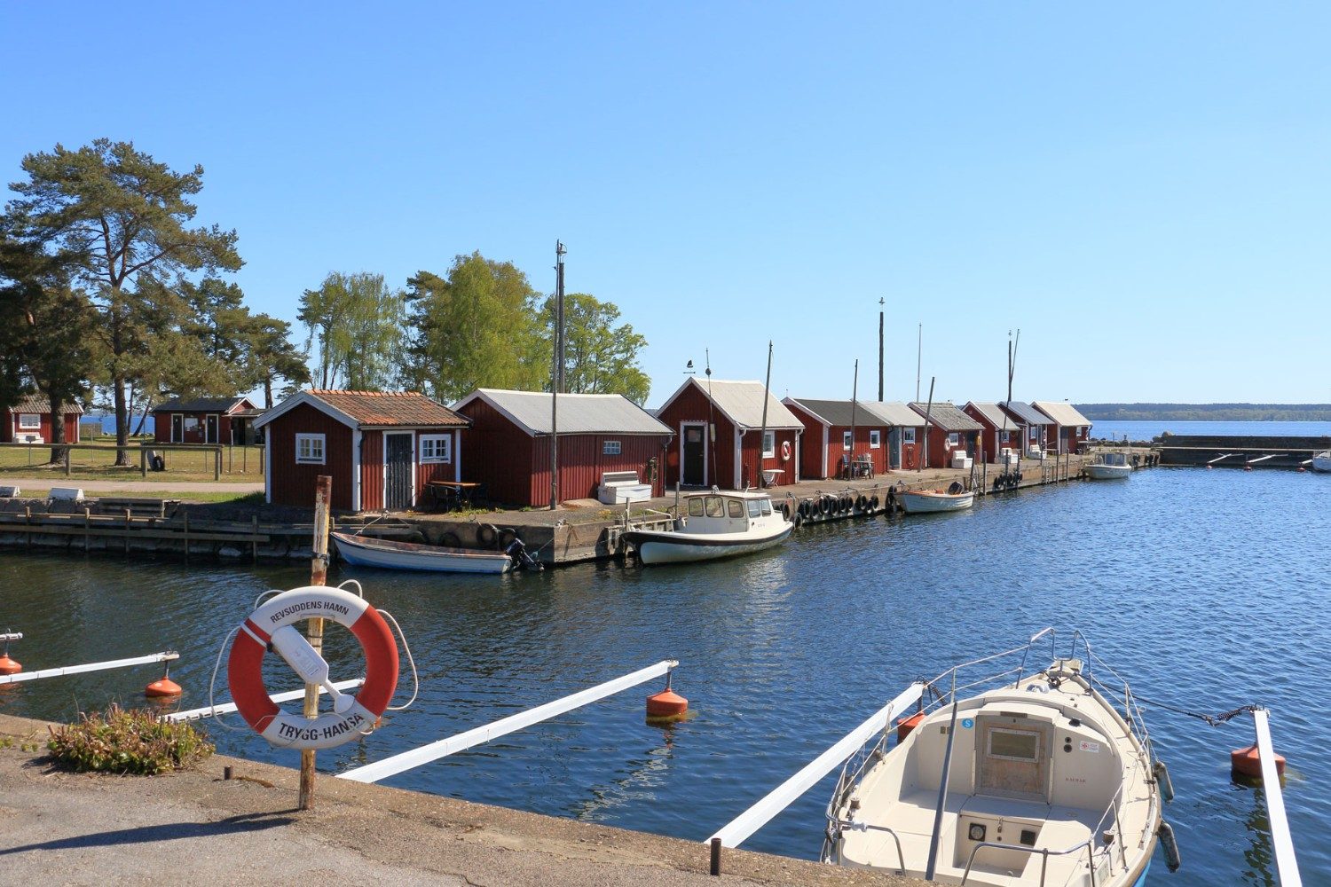Revsuddens hamn med röda sjöbodar och båtar en solig dag